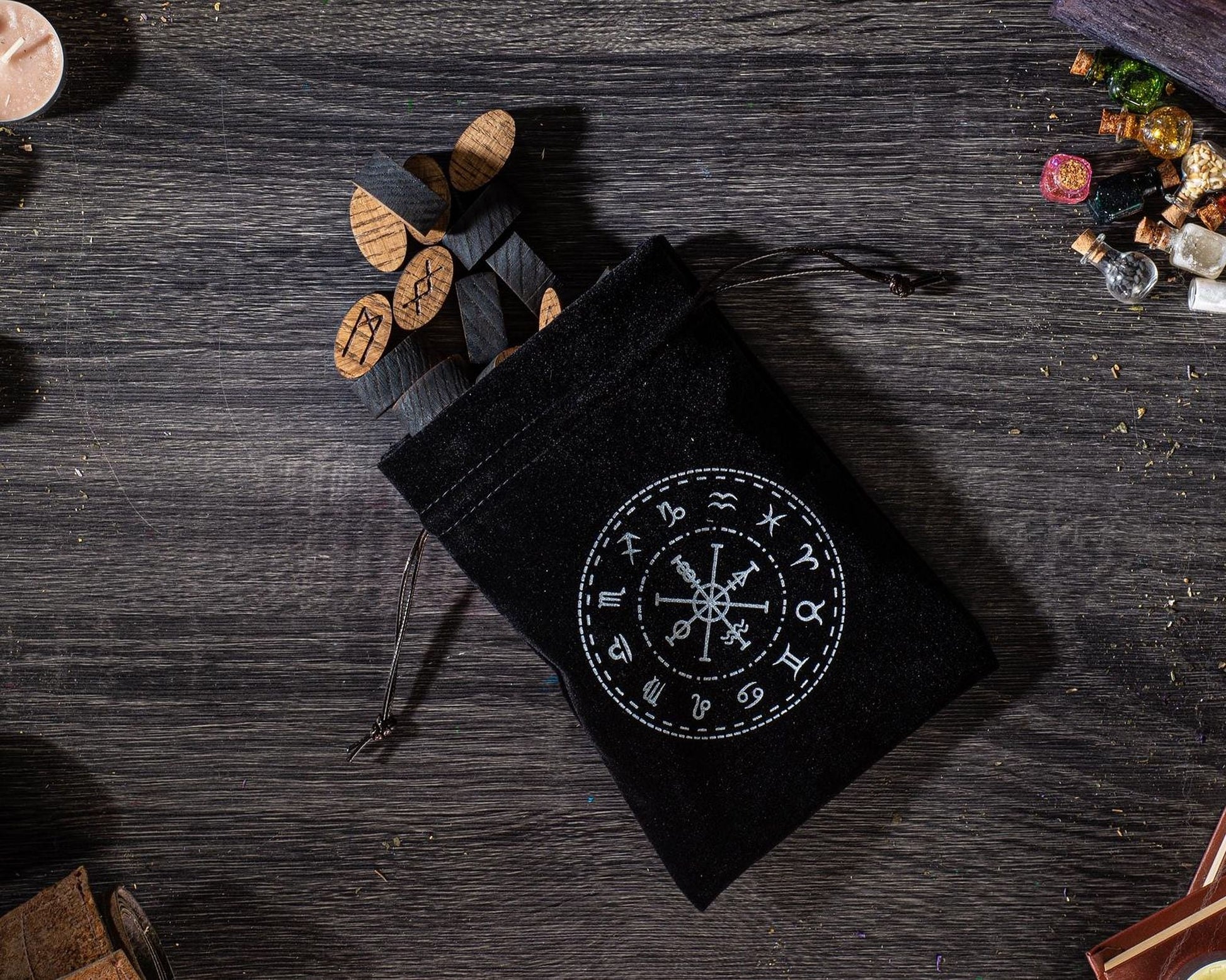 A black pouch with a white design on it, containing several wooden sticks, is placed on a wooden surface.