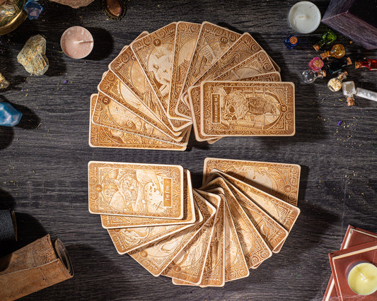 a collection of ornate wooden cards arranged in a circular pattern on a dark wooden surface, surrounded by various objects such as candles, gemstones, and books.