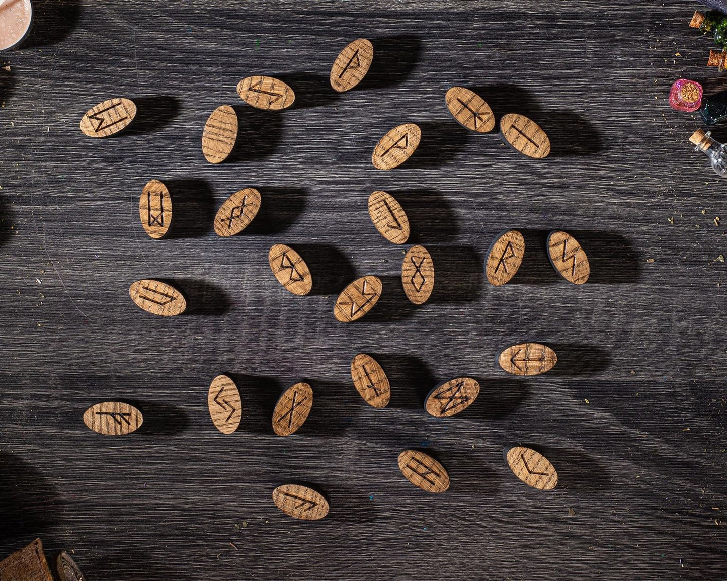 a collection of wooden beads or charms with various symbols or markings on them, arranged on a dark wooden surface.