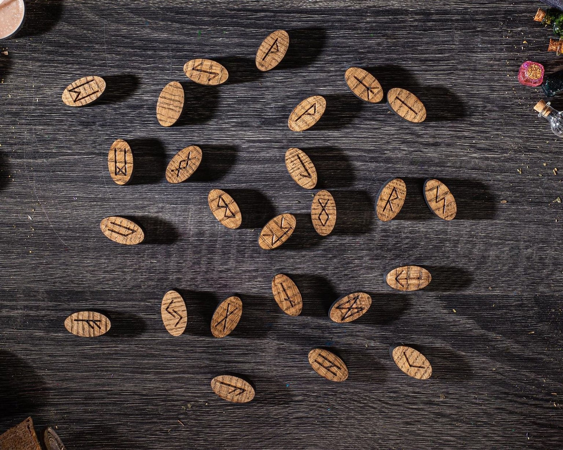 a collection of wooden beads or charms with various symbols or markings on them, arranged on a dark wooden surface.