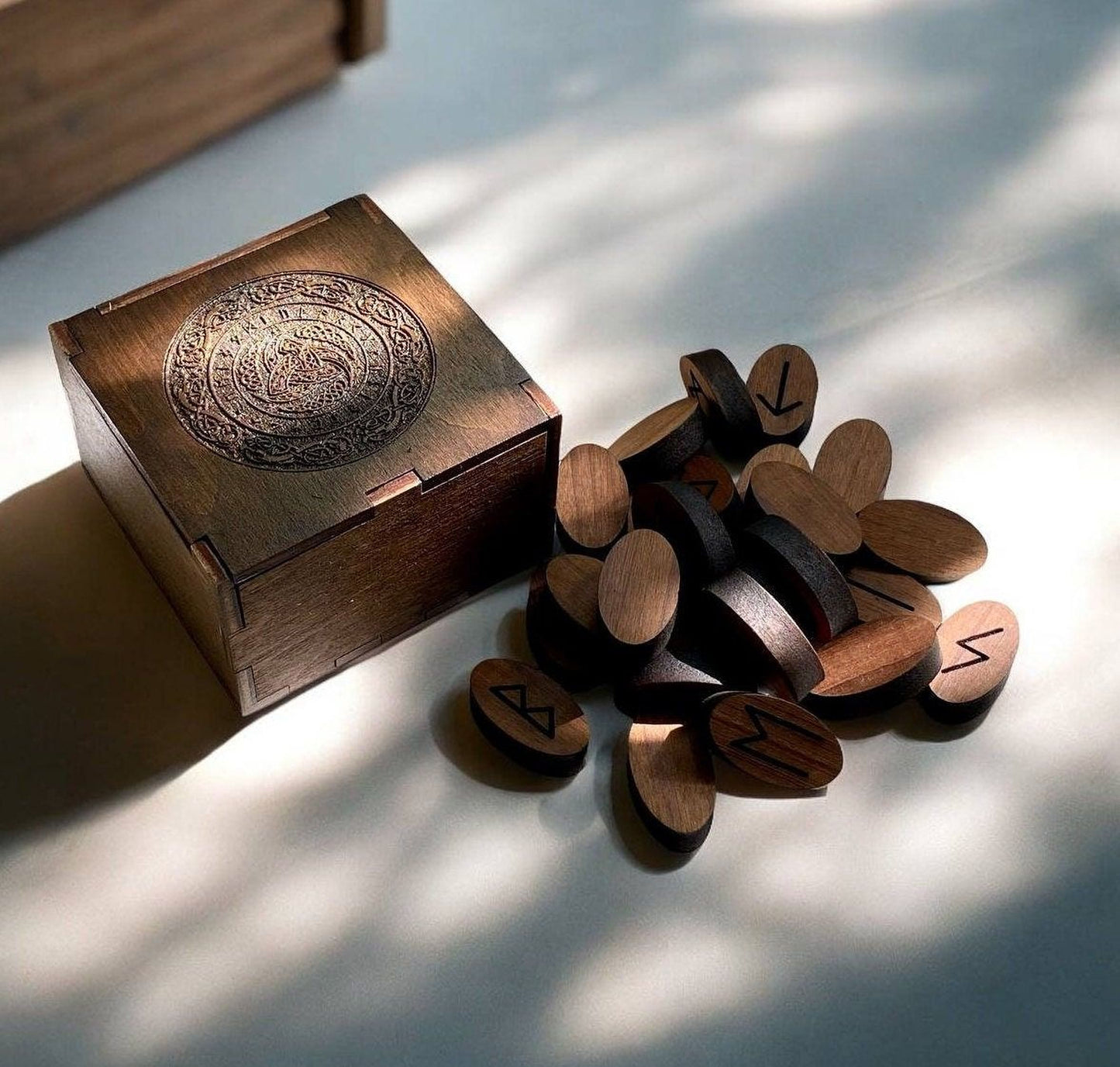 a wooden box with a carved design on the lid, and a pile of wooden objects with various symbols on them, including what appear to be wooden wedges or blocks.
