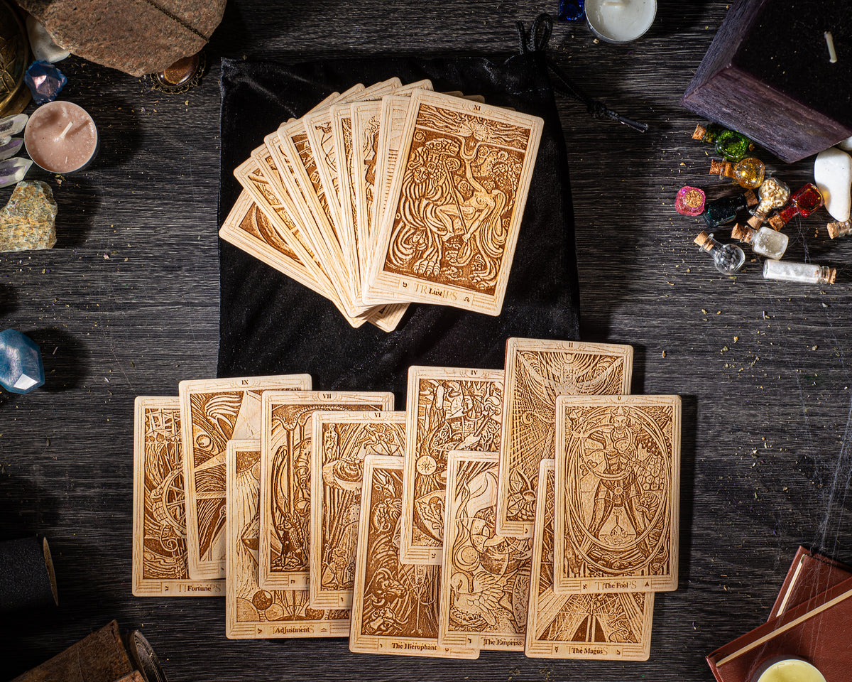 a collection of wooden tarot cards arranged on a wooden surface, along with various objects such as crystals, candles, and a black cloth.