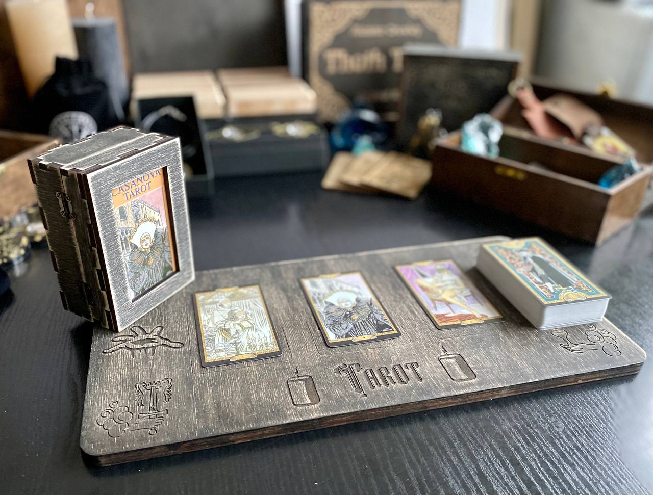 a wooden board with three tarot cards on it, along with a small wooden box and other items on a table.