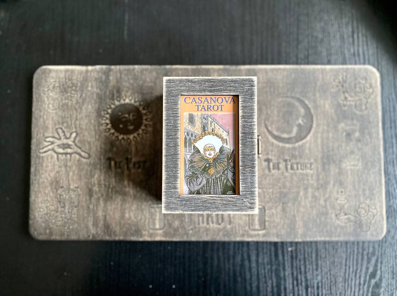 a tarot card box with a Casanova tarot card inside, placed on a wooden surface.