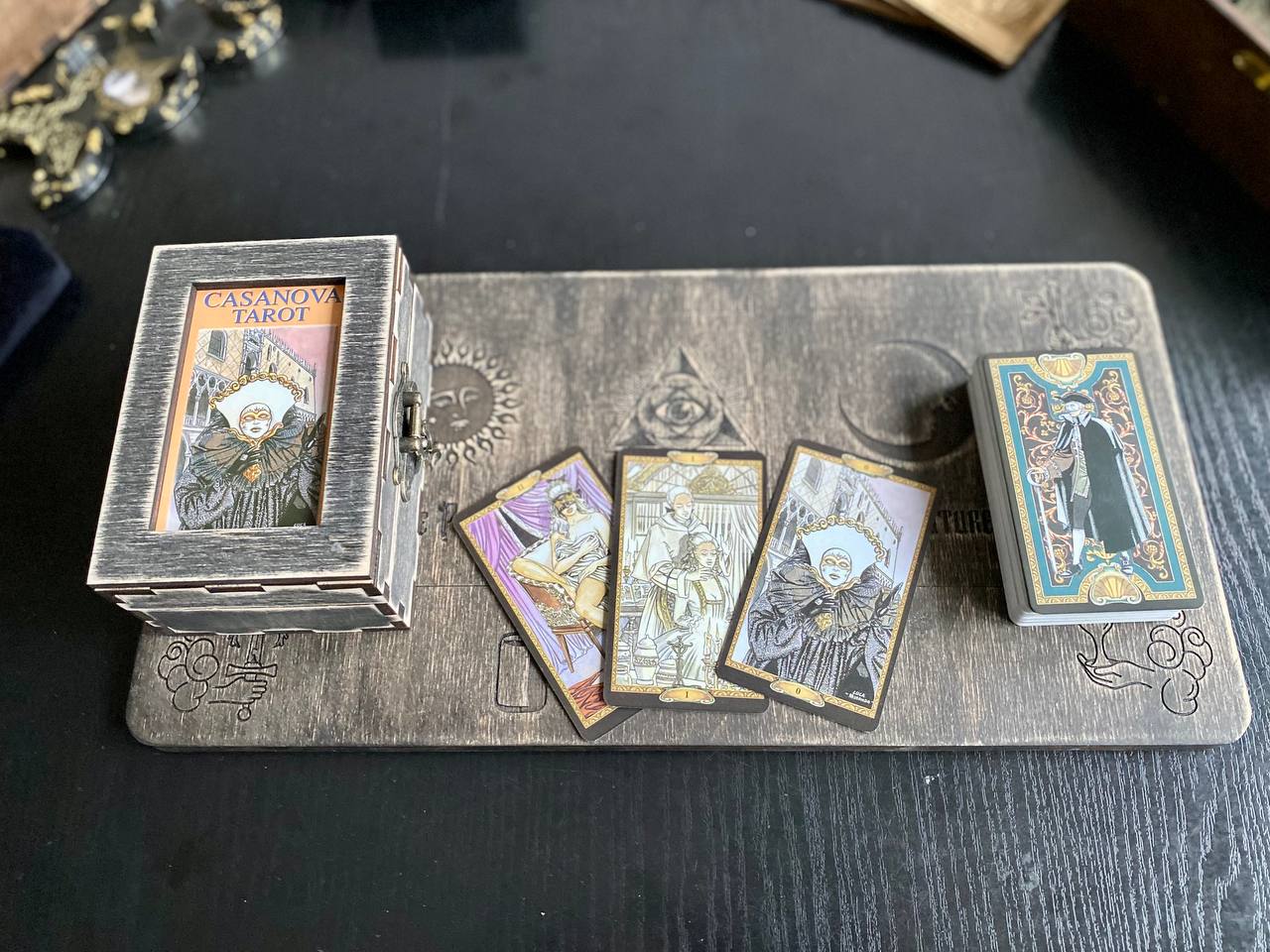 a tarot deck with a wooden board and a set of playing cards, including a Casanova Tarot deck.
