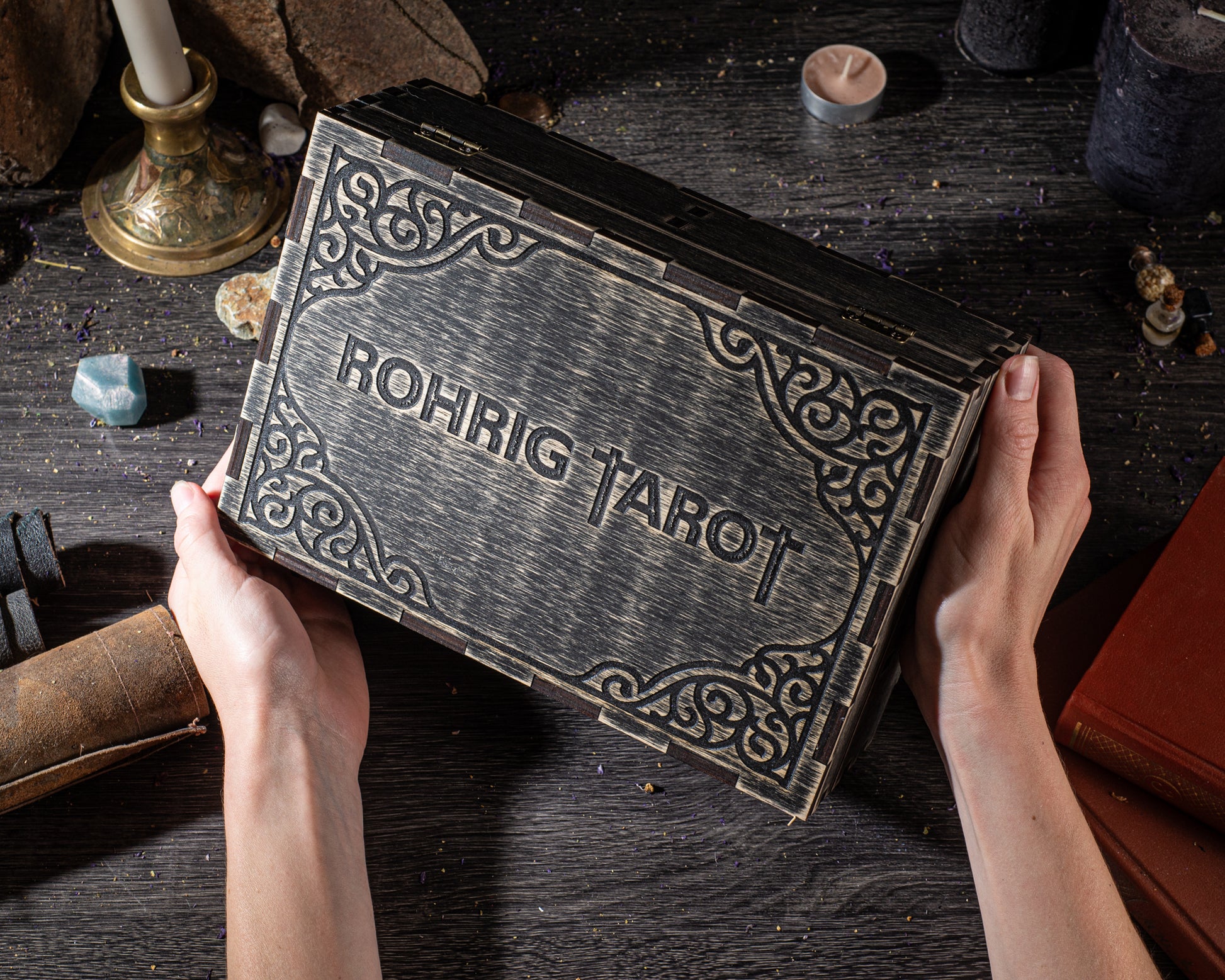 A person's hands holding a large, ornate book titled "Rohrig Tarot" on a dark wooden surface.