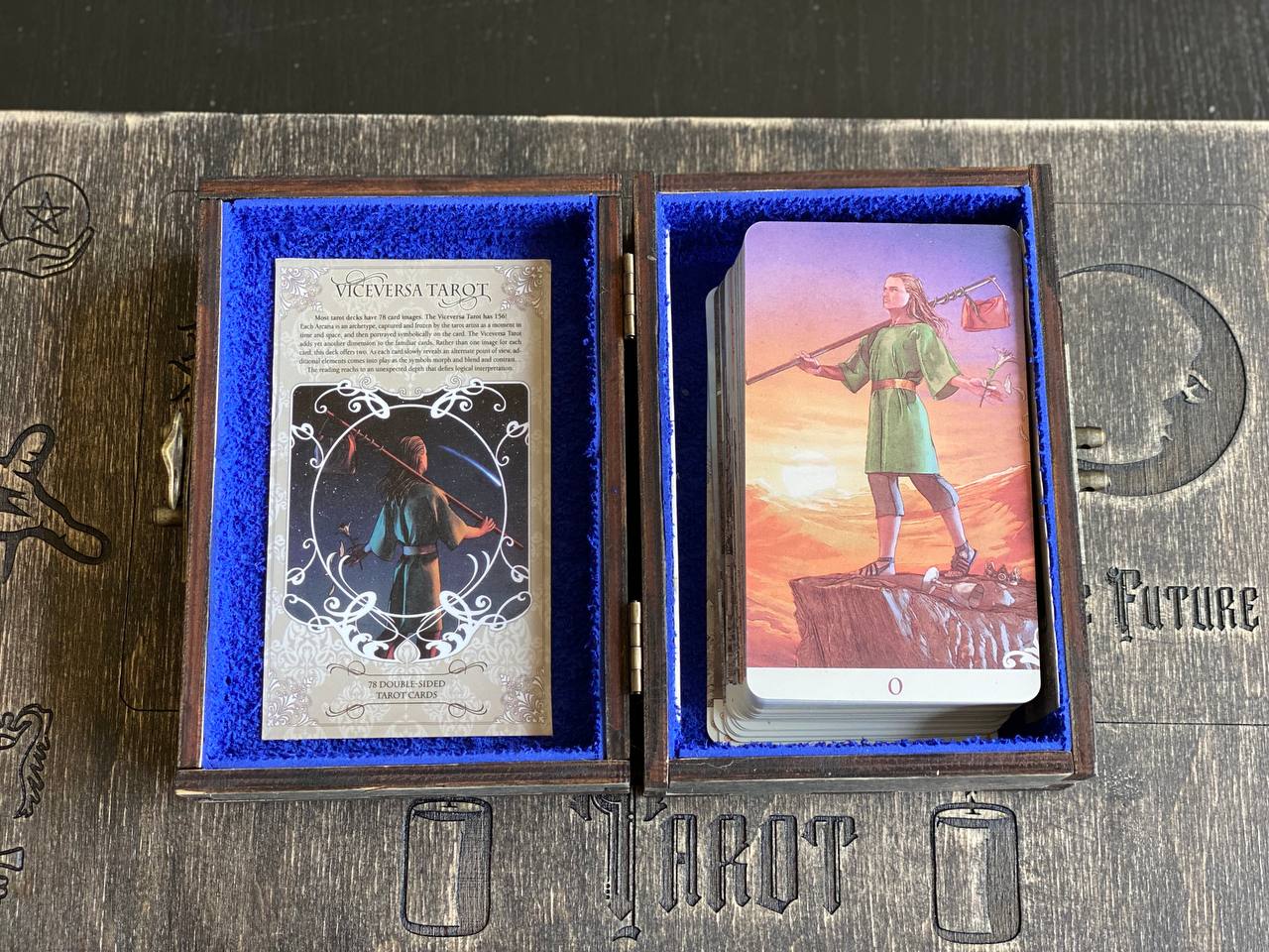 a tarot deck with a blue-framed box containing the deck's cards and a card visible inside the box.