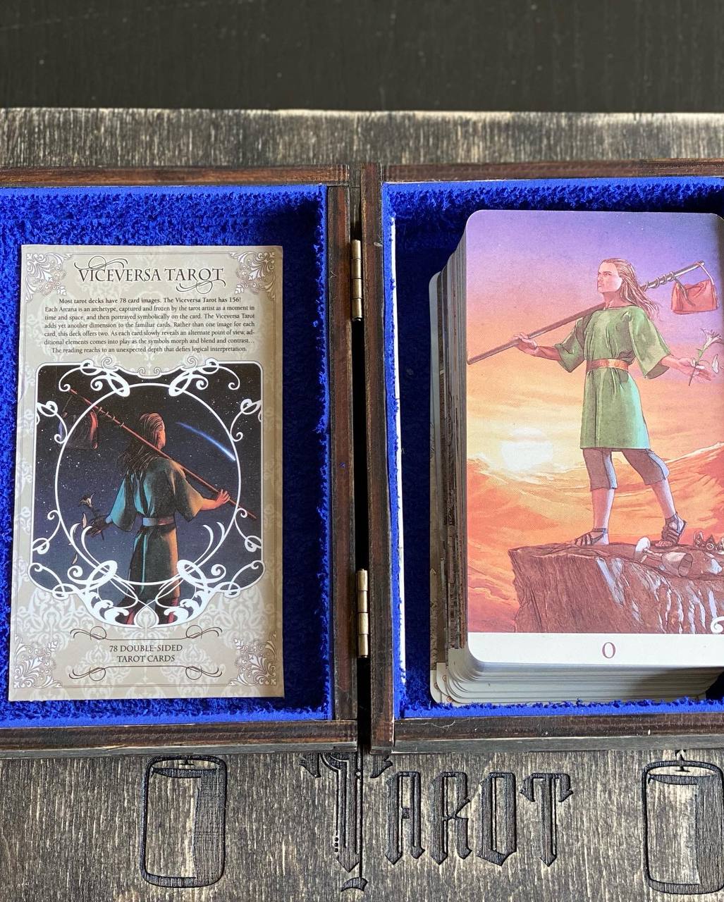 a tarot deck with a blue interior and wooden exterior, containing a tarot card and a card with a figure on it.