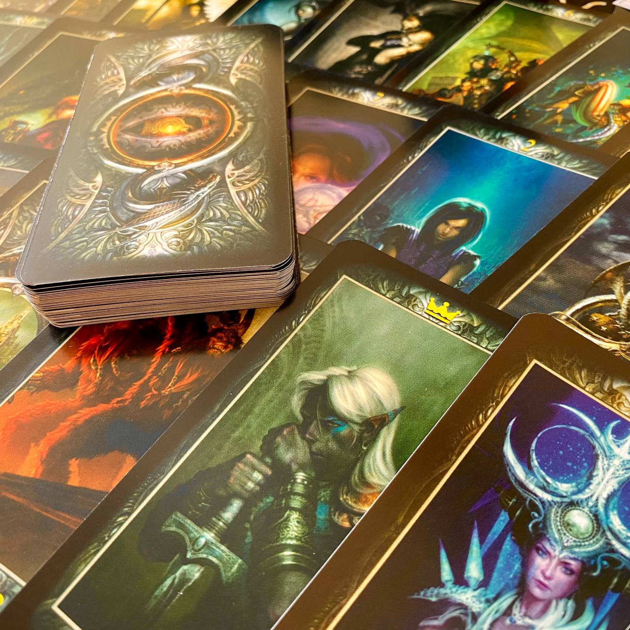 a collection of fantasy-themed tarot cards, including a central card with an eye design and a stack of cards on top.