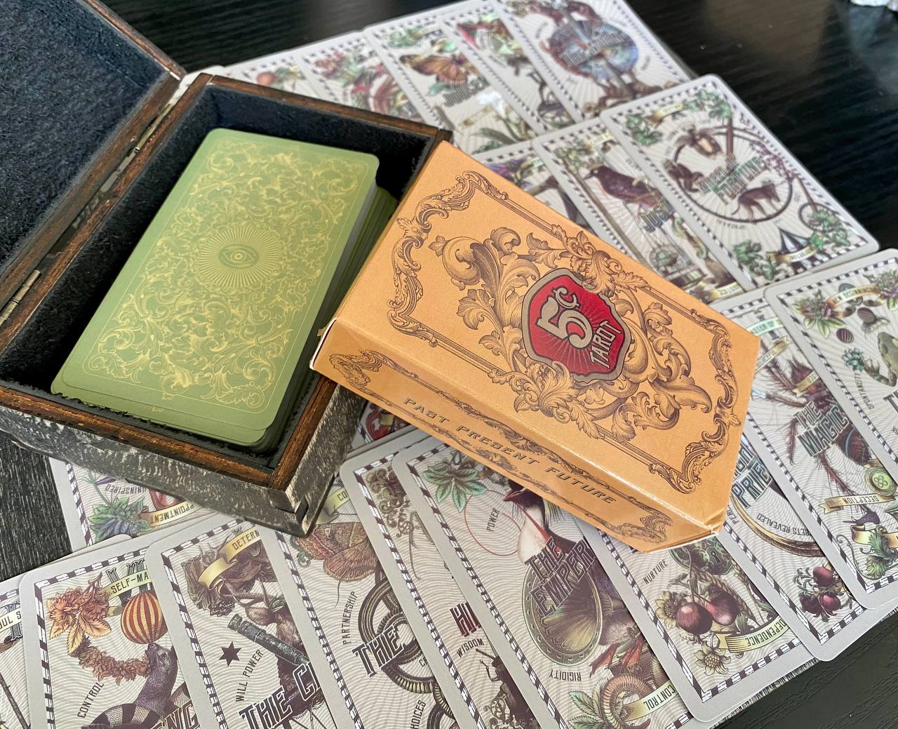 a wooden box with a green card inside, and several other cards are scattered around it on a table.