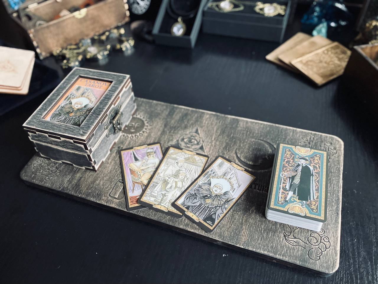 a collection of tarot cards and a wooden box on a dark surface, possibly a table.