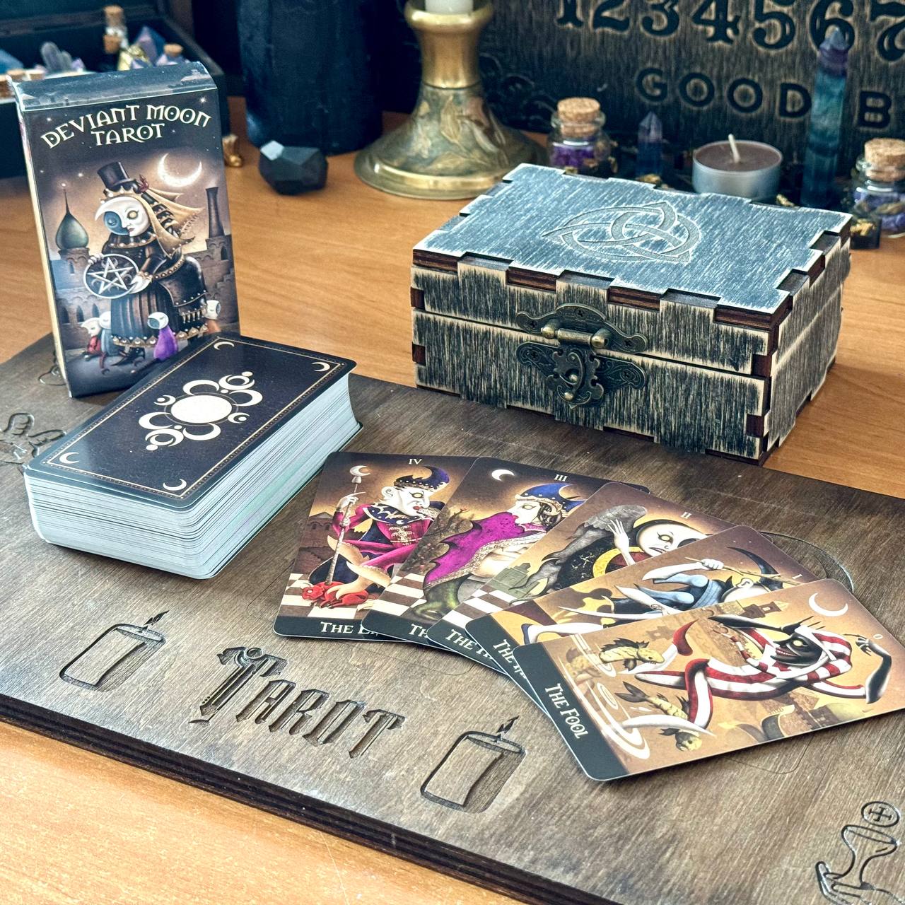 a tarot deck, including a deck of cards and a wooden box, arranged on a wooden surface.