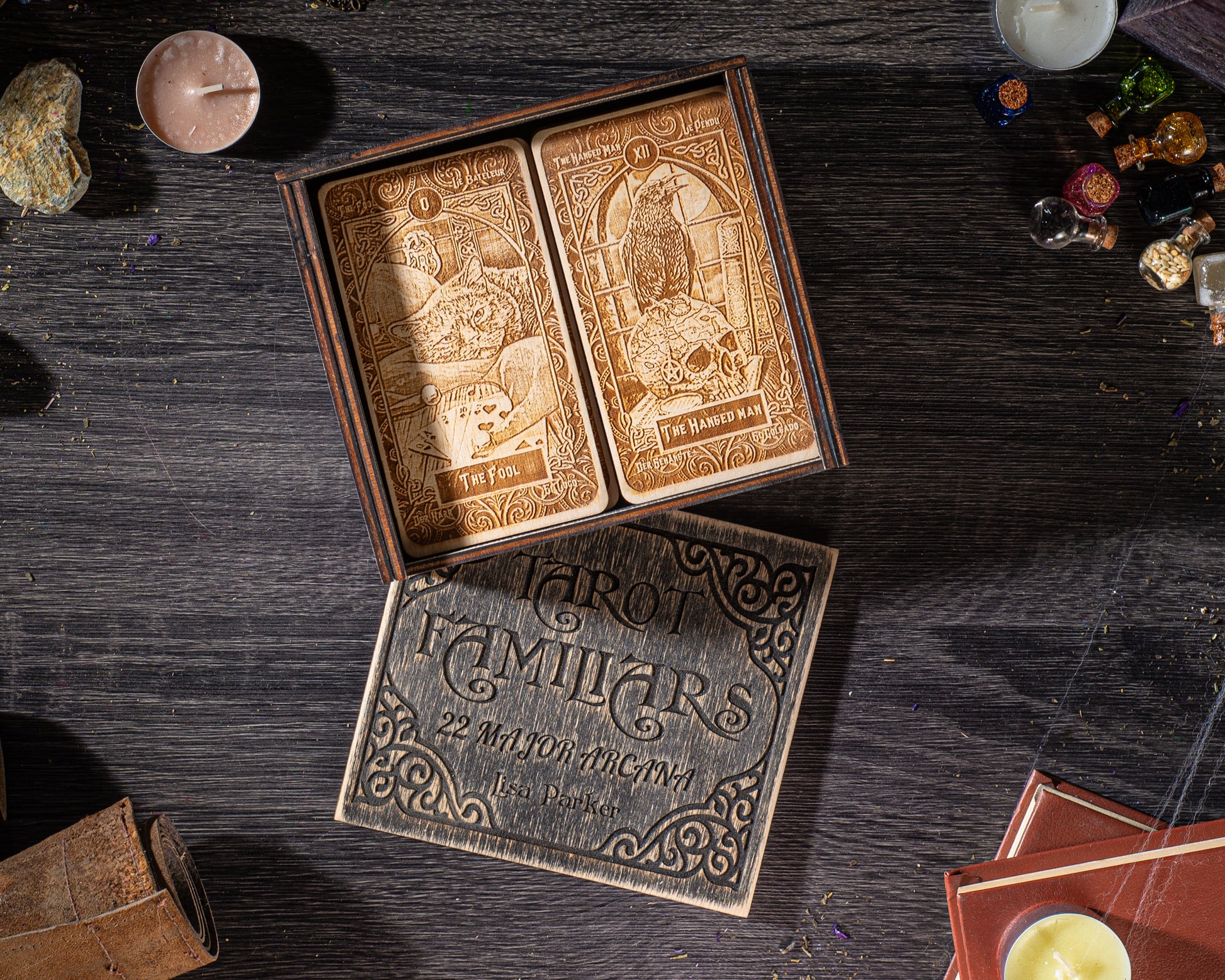 a tarot card box with a wooden lid, displaying a set of two ornately decorated tarot cards, one inside the box and the other open on the table.