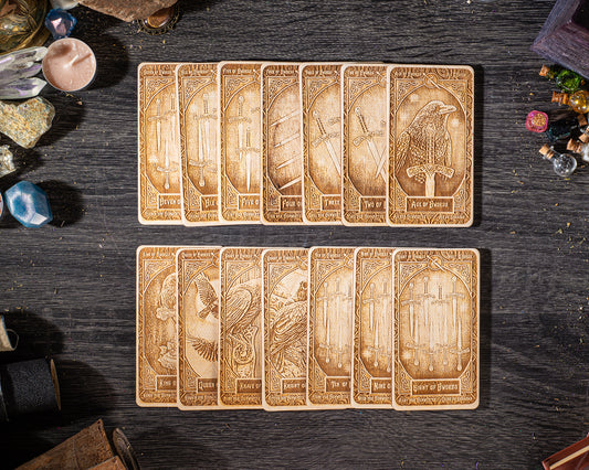 A collection of wooden tarot cards with intricate designs and illustrations, arranged on a dark wooden surface.