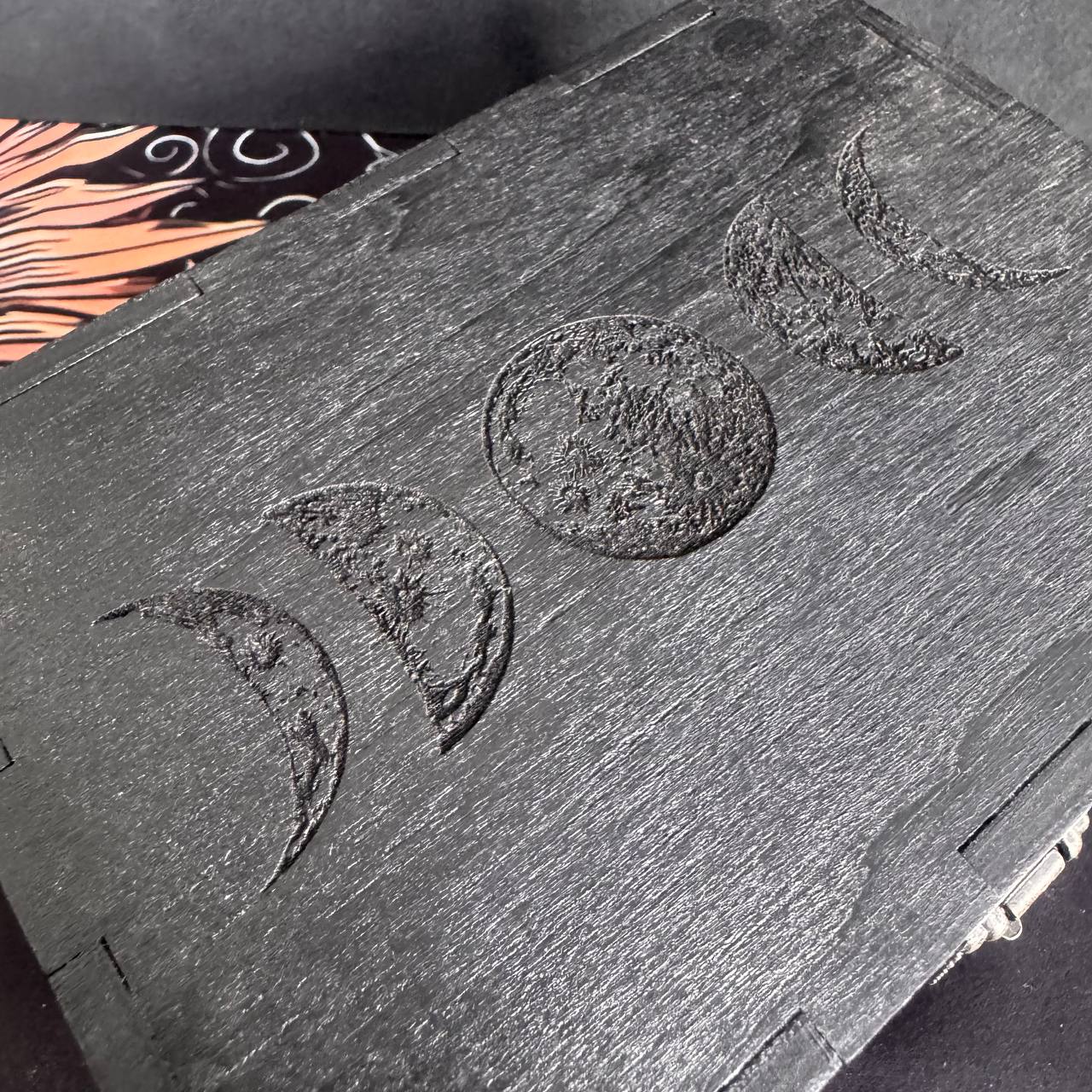 a close-up view of a wooden box with a carved design on its surface, depicting the phases of the moon.