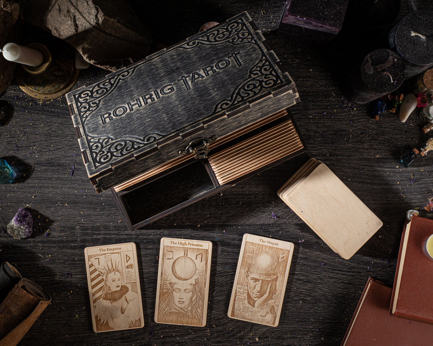 a wooden box with a carved design, along with three tarot cards and various objects on a dark surface.