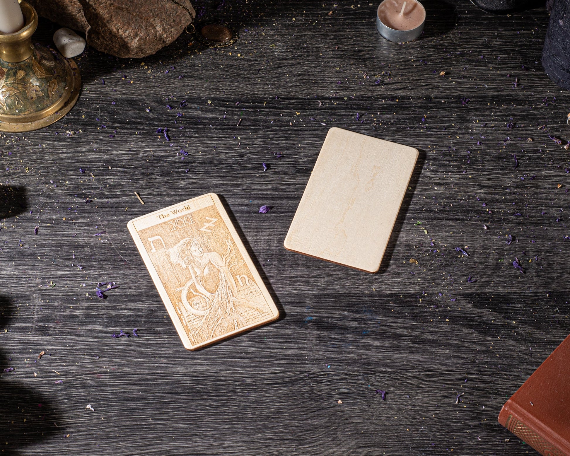 a tarot card and a wooden coaster on a dark wooden surface, with some scattered purple objects around them.