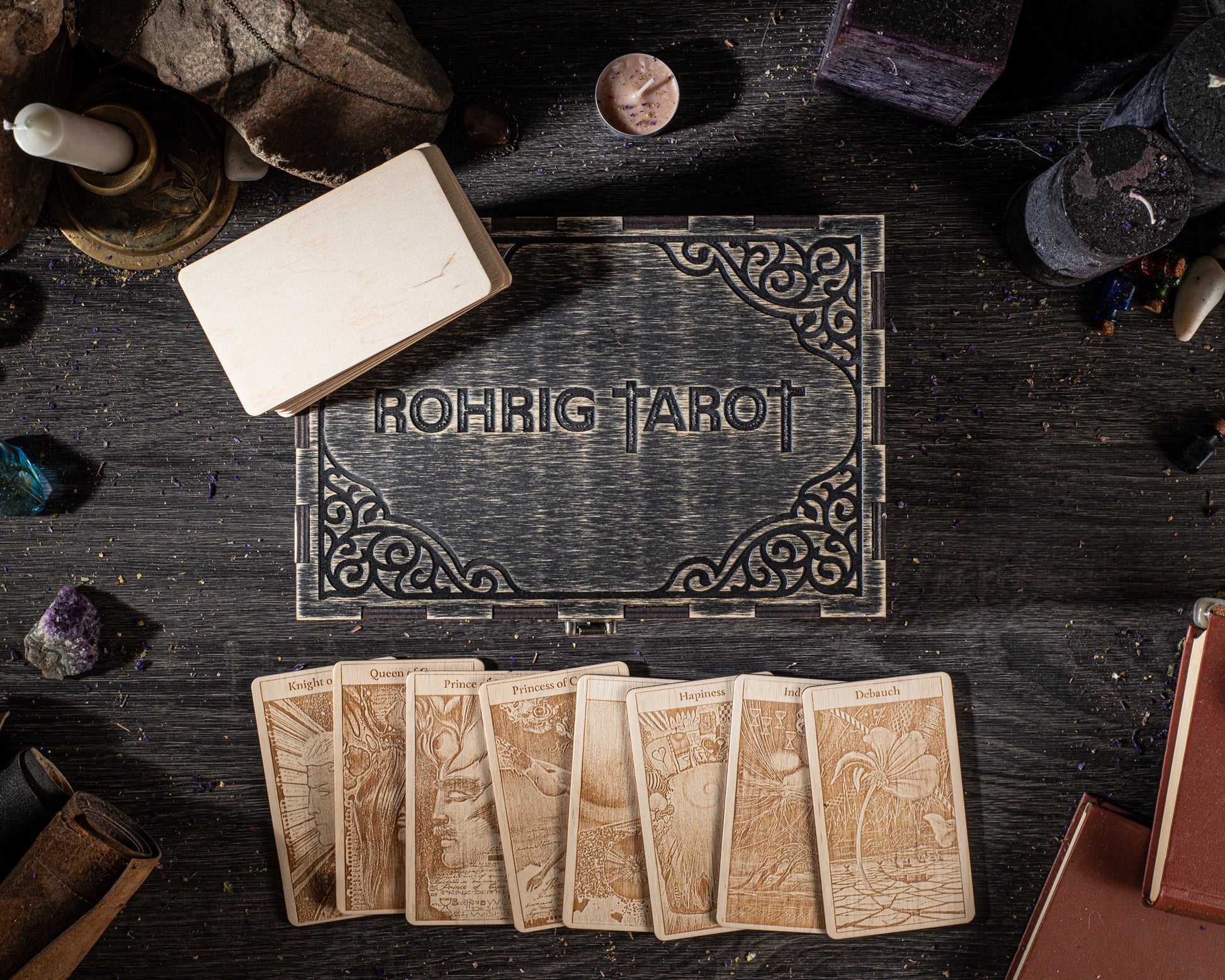 a collection of tarot cards, a wooden box, and various objects such as candles and crystals arranged on a dark surface.