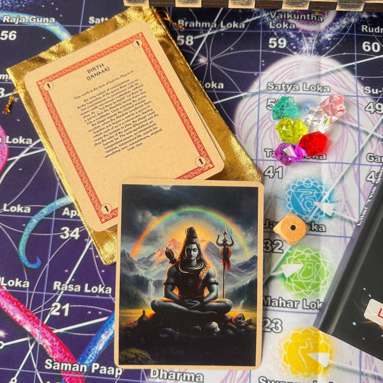 a card with a depiction of a Hindu deity, a map of the Hindu universe, and various objects such as a crystal ball, a book, and a deck of cards.