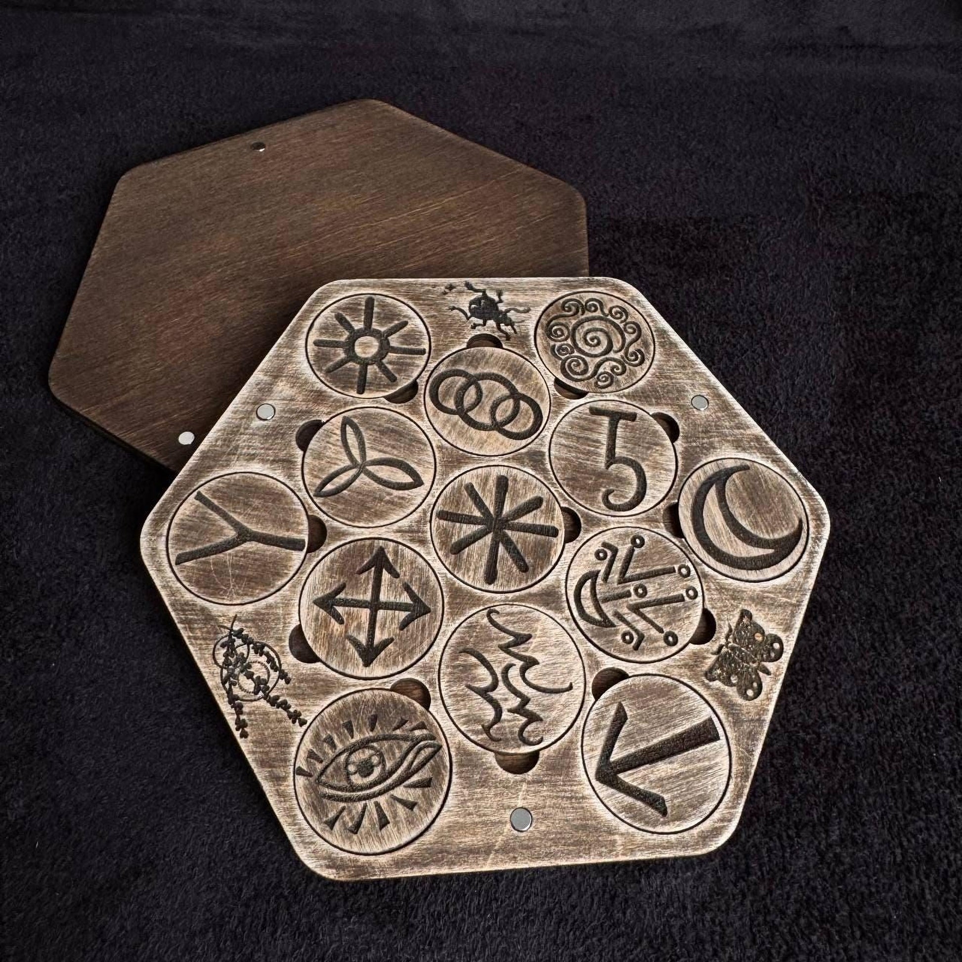a wooden board with various symbols and designs carved into it, including a hexagon with a star and a crescent moon, as well as other circular and geometric patterns.