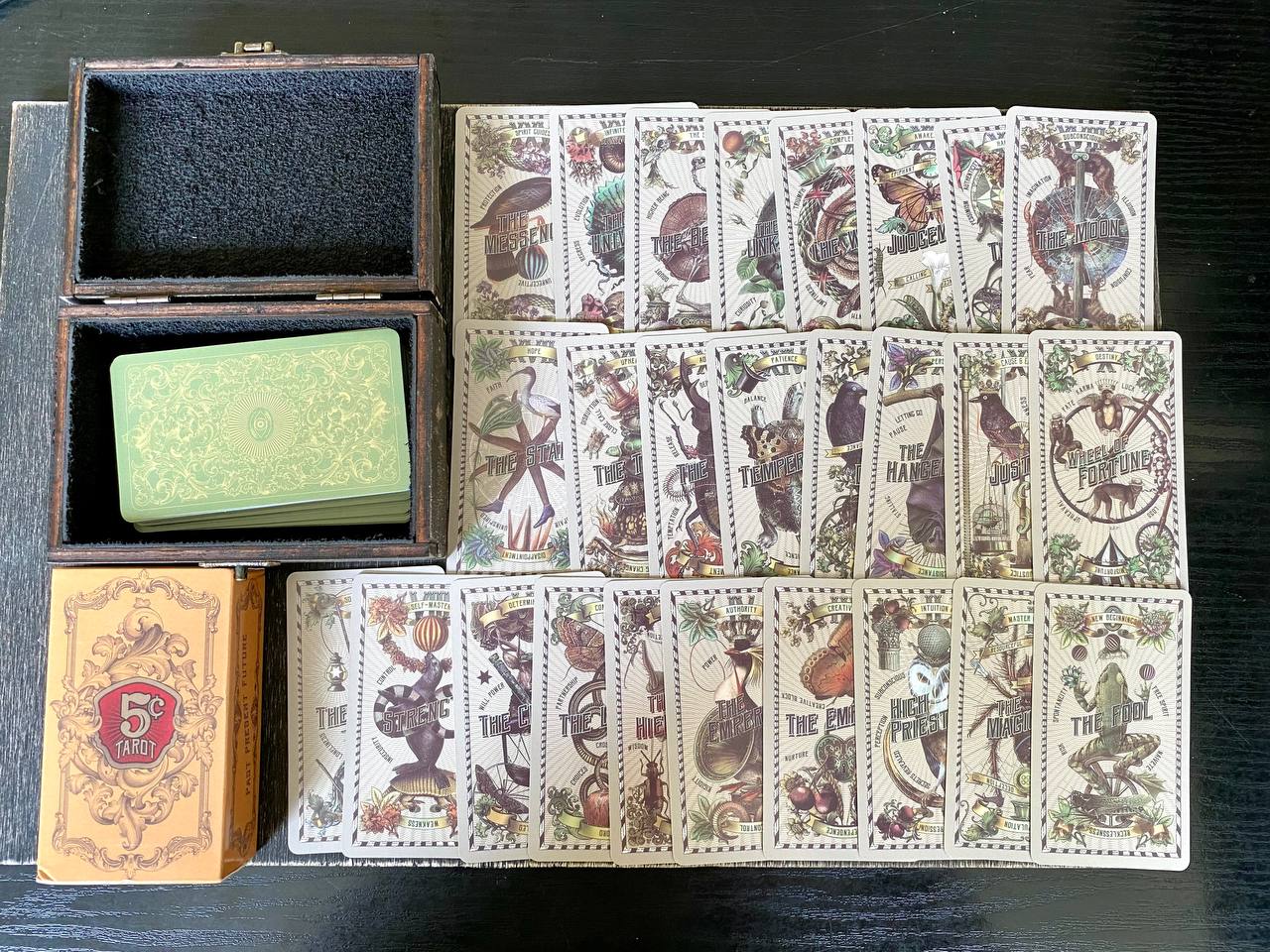 a collection of tarot cards and a wooden box, arranged on a dark surface.