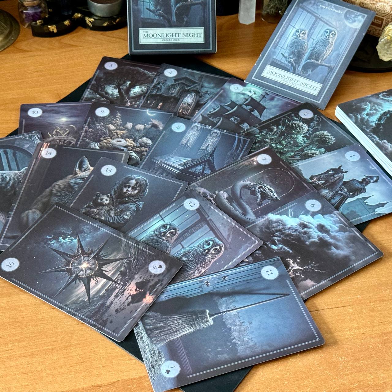 a collection of cards with various illustrations and scenes, including owls, a house, and a star, all set against a dark and moody background.