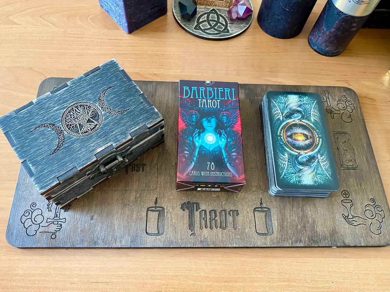a collection of tarot cards and a wooden box on a wooden surface.