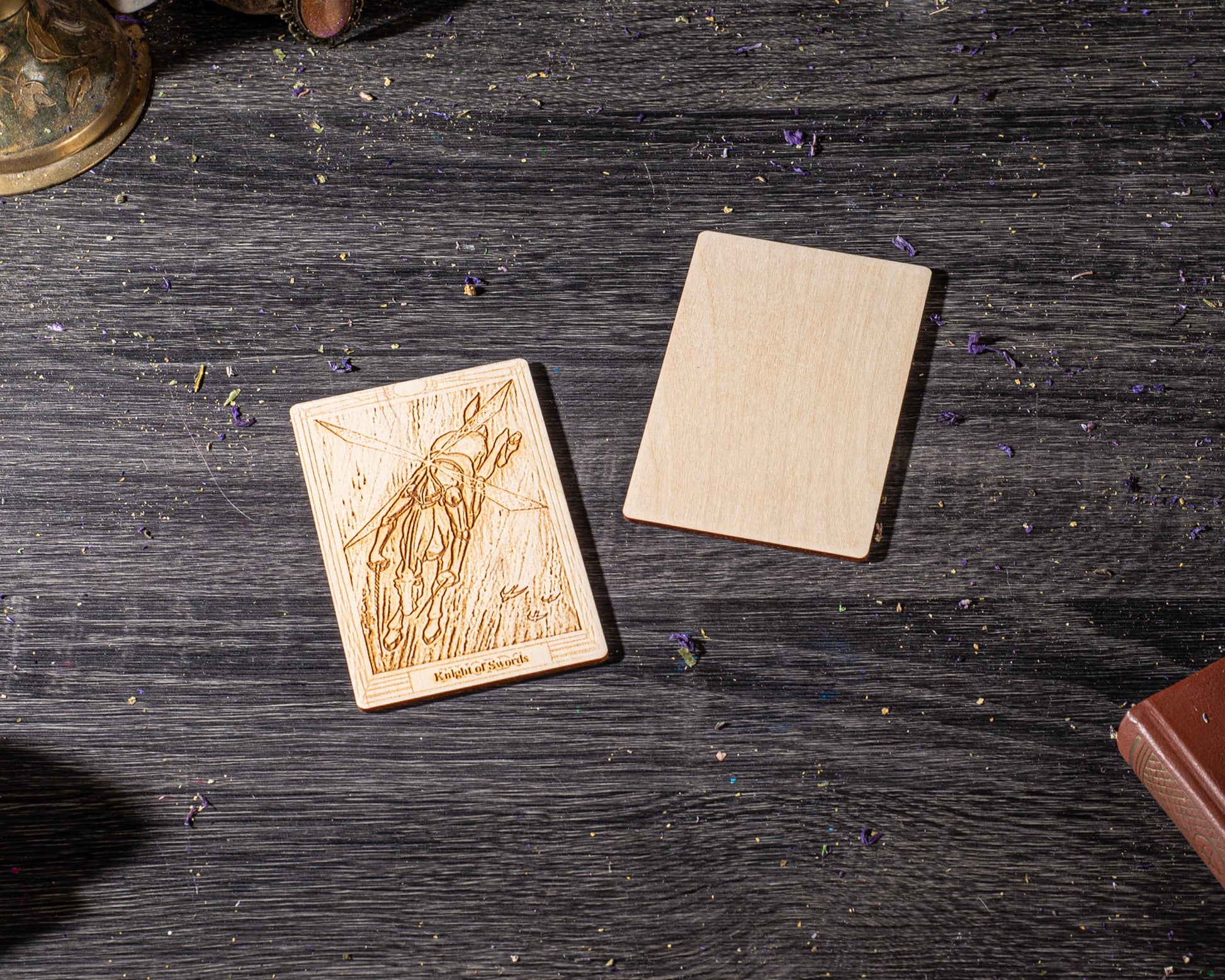 a wooden card with an embossed design and a blank wooden card on a dark wooden surface.
