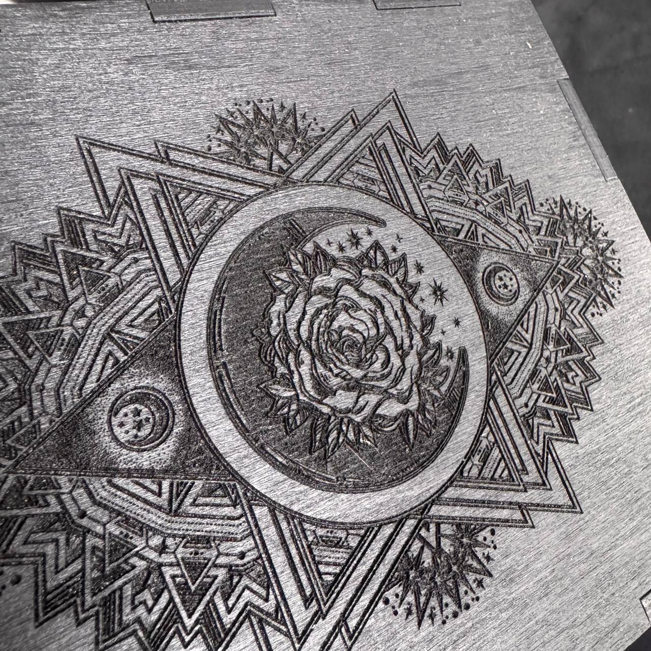 a detailed engraved design with a central rose surrounded by various geometric shapes and patterns.