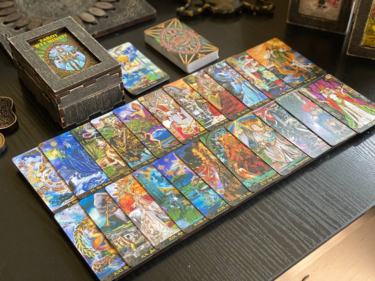 a collection of colorful tarot cards arranged on a wooden surface, along with a small wooden box and some other items.