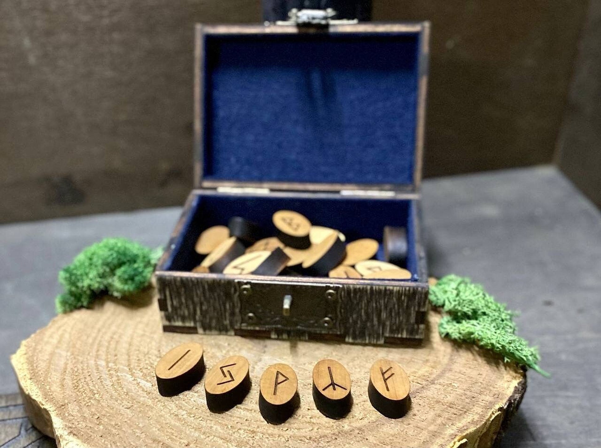 a wooden box with a blue interior, containing several wooden pieces, and a wooden board with the word "ISP" carved into it.