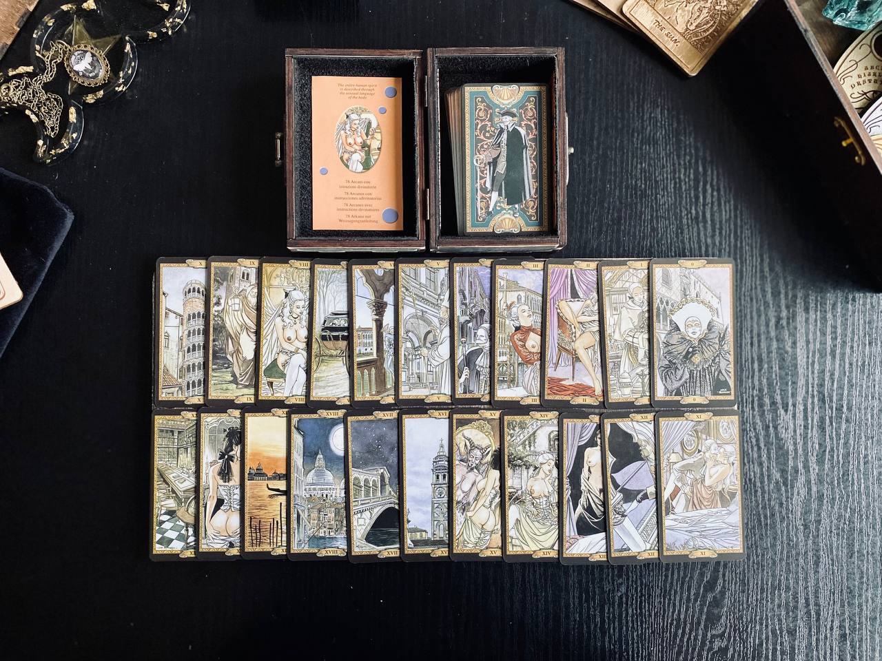 a collection of tarot cards arranged on a dark surface, with some cards in a wooden box and others spread out on the table.