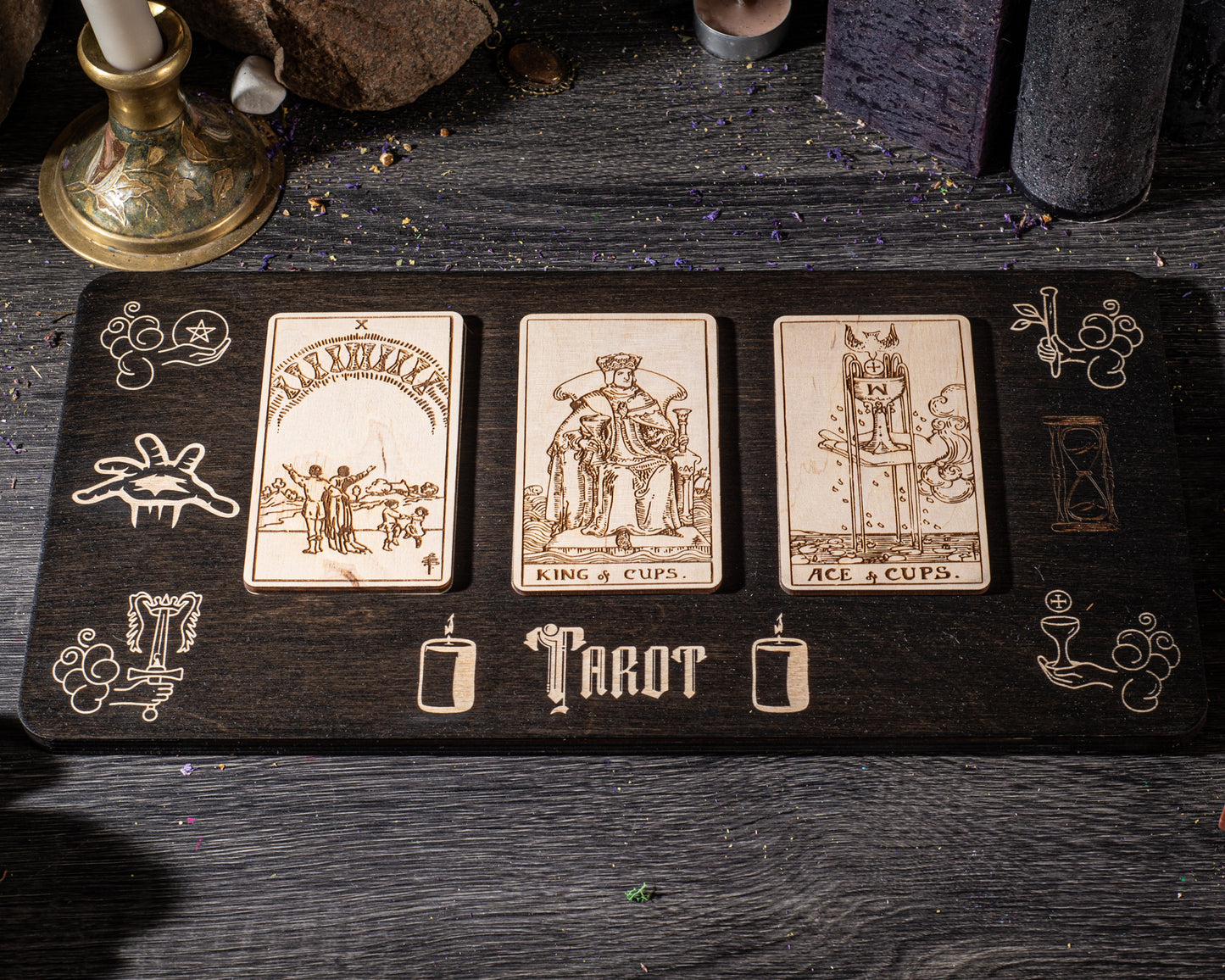 A wooden board displaying three tarot cards with illustrations and text, placed on a dark wooden surface.