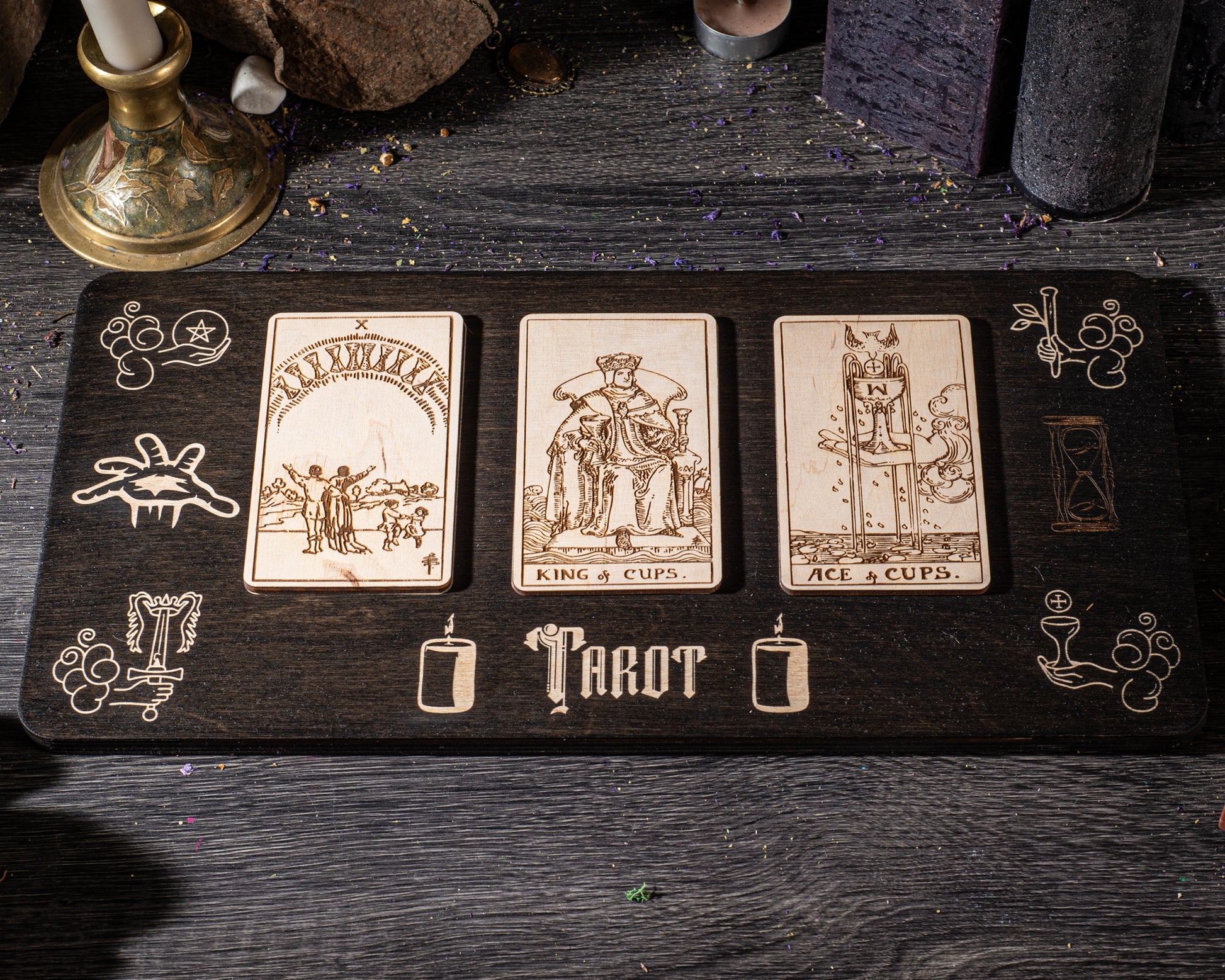 A wooden board displaying three tarot cards with illustrations and text, placed on a dark wooden surface.