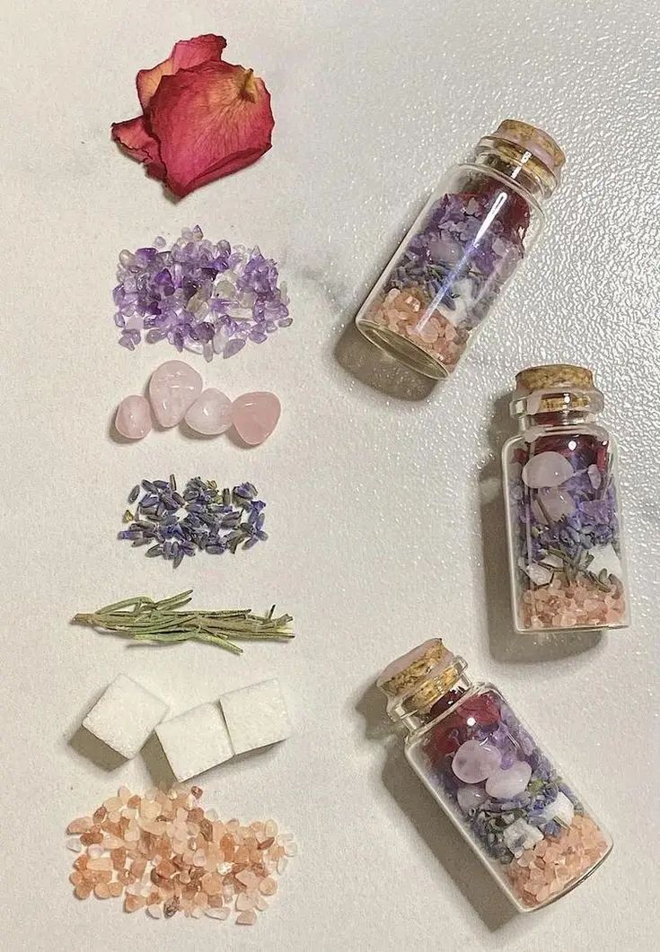 Small glass spell bottles filled with colorful dried flowers and herbs on a light surface.