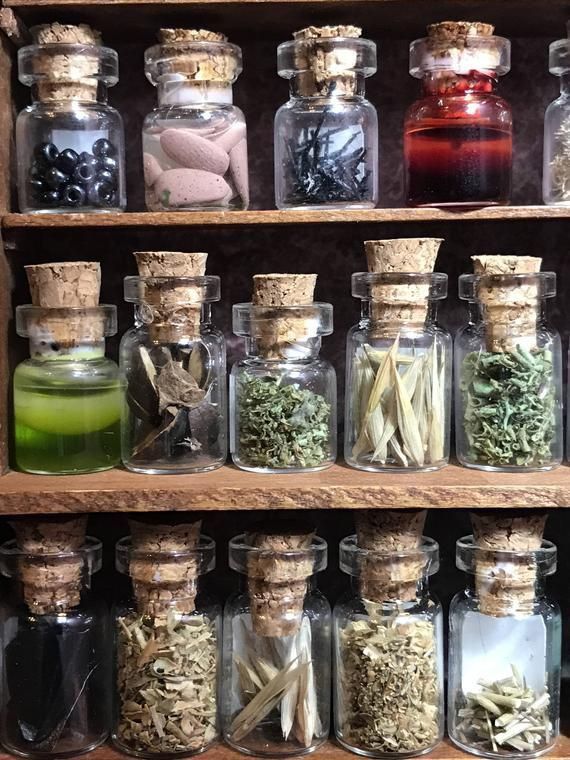 Collection of spell glass jars with cork lids containing various herbs and substances on a wooden shelf.