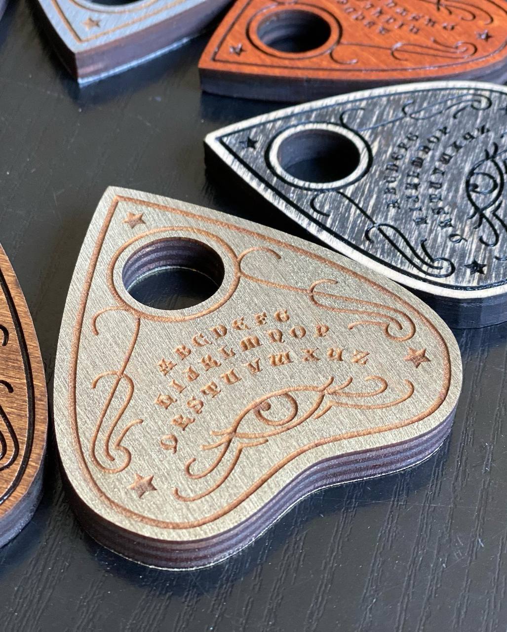 Close-up of wooden planchette showing detailed engraving and smooth finish